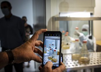 A journalist takes a cell phone photo of a scientist working on the development of Abdala, an experimental vaccine for COVID-19, at the Center for Genetic Engineering and Biotechnology (CIGB) in Havana, Cuba, Thursday, Feb. 25, 2021. (AP Photo/Ramon Espinosa)