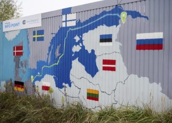 Nápis "Nord Stream 2 Committed. Spoľahlivý. Bezpečný." visí nad namaľovanou mapou plynovodu Nord Stream 2 z Ruska do Nemecka na odbernej stanici zemného plynu v priemyselnej zóne Lubmin v nemeckom Lubmine 16. novembra 2021 (Foto: SITA/AP/Stefan Sauer/dpa)