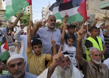 Palestínčania mávajú svojimi národnými vlajkami, dvíhajú ruky a skandujú heslá počas zhromaždenia (Foto: SITA/AP Photo/Adel Hana)
