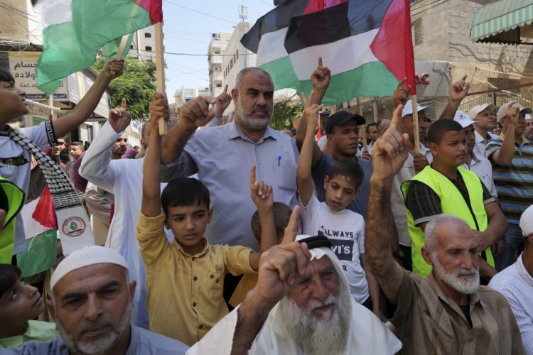 Palestínčania mávajú svojimi národnými vlajkami, dvíhajú ruky a skandujú heslá počas zhromaždenia (Foto: SITA/AP Photo/Adel Hana)