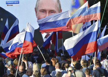 Ľudia sledujú na veľkoplošnej obrazovke, ako ruský prezident Vladimir Putin prednáša svoj prejav po slávnostnom podpise zmlúv o pripojení štyroch regiónov Ukrajiny k Rusku v moskovskom Kremli počas stretnutia v Sevastopole na Kryme v piatok 30. septembra 2022. (Foto: SITA/AP Photo)