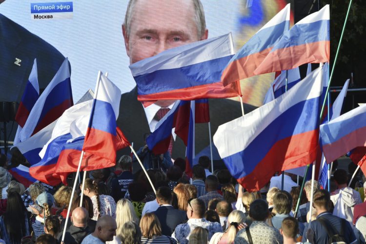 Ľudia sledujú na veľkoplošnej obrazovke, ako ruský prezident Vladimir Putin prednáša svoj prejav po slávnostnom podpise zmlúv o pripojení štyroch regiónov Ukrajiny k Rusku v moskovskom Kremli počas stretnutia v Sevastopole na Kryme v piatok 30. septembra 2022. (Foto: SITA/AP Photo)