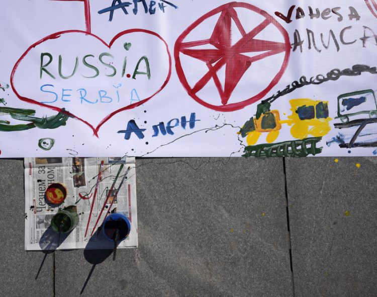 Kresby a slogany sú namaľované na veľkej plachte na chodníku pri príležitosti 23. výročia začiatku 78-dňového bombardovania Srbskom vedenej Juhoslávie zo strany NATO na Námestí republiky v Belehrade, Srbsko, štvrtok 24. marca 2022 (Foto: SITA/AP Photo/Darko Vojinovič)