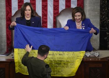 Viceprezidentka Kamala Harrisová a predsedníčka Snemovne reprezentantov Nancy Pelosiová z Kalifornie (vpravo) reagujú na ukrajinského prezidenta Volodymyra Zelenského, ktorý počas prejavu na spoločnom zasadnutí Kongresu na Kapitole vo Washingtone v stredu 21. decembra 2022 odovzdáva zákonodarcom ukrajinskú vlajku s autogramom frontových jednotiek v Bachmute v ukrajinskej spornej Doneckej provincii (Foto: SITA/AP Photo/Jacquelyn Martin)
