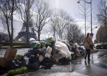 Žena prechádza okolo hromady nevyvezeného odpadu neďaleko Eiffelovej veže v Paríži v piatok 24. marca 2023. (Foto: SITA/AP Photo/Thomas Padilla)