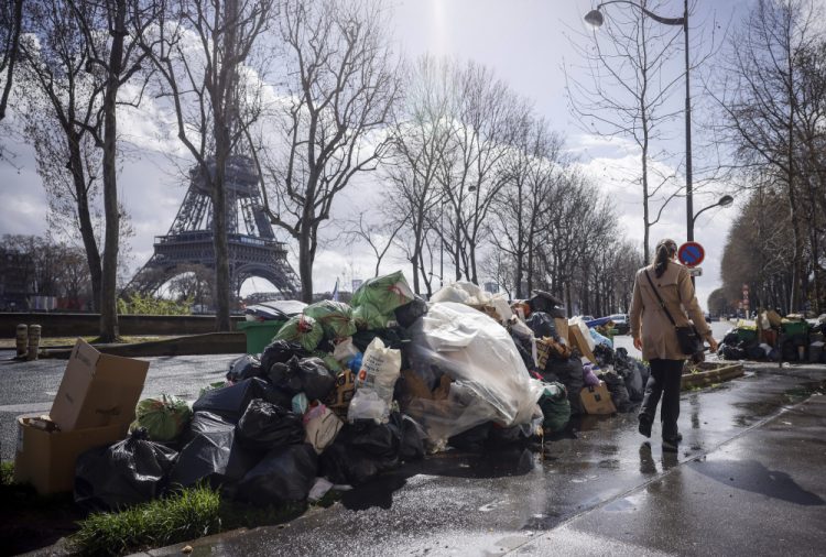 Žena prechádza okolo hromady nevyvezeného odpadu neďaleko Eiffelovej veže v Paríži v piatok 24. marca 2023. (Foto: SITA/AP Photo/Thomas Padilla)