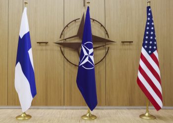 Vlajky Fínska, NATO a USA (zľava) stoja pred logom NATO počas stretnutia ministrov zahraničných vecí NATO v sídle NATO v Bruseli v utorok 4. apríla 2023 (Foto: SITA/AP/Johanna Geron)