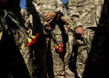 Ukrajinskí vojaci držia kvety počas rozlúčky s Nicholasom Maimerom, americkým občanom a armádnym veteránom, ktorý bol zabitý počas bojov pri Bachmute (Foto: SITA/AP Photo/Evgeniy Maloletka)