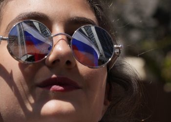 Ruská vlajka sa odráža v slnečných okuliaroch ženy počas pochodu libanonských a ruských občanov na Deň víťazstva Ruska v libanonskom Bejrúte v nedeľu 8. mája 2022 (Foto: SITA/AP Photo/Hassan Ammar)