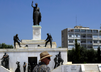 Turista stojí pred sochou vojaka (Foto: SITA/AP Photo/Petros Karadjias)