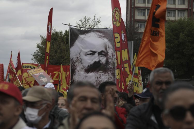 Tisíce ľudí mávajú vlajkami a transparentmi vrátane obrovského plagátu nemeckého filozofa Karla Marxa počas prvomájového protestu v tureckej Ankare v nedeľu 1. mája 2022. Turecká poriadková polícia rýchlo zasiahla v Istanbule a obkľúčila protestujúcich neďaleko zamrežovaného námestia Taksim, kde v roku 1977 počas prvomájového podujatia zahynulo 34 ľudí, keď sa do davu strieľalo z neďalekej budovy (Foto: SITA/AP Photo/Burhan Ozbilici)