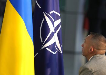 Člen protokolu vztyčuje vlajky NATO a Ukrajiny pred mediálnou konferenciou ukrajinského prezidenta Volodymyra Zelenského a generálneho tajomníka NATO Jensa Stoltenberga počas stretnutia ministrov obrany NATO v sídle NATO v Bruseli v stredu 11. októbra 2023 &&äFoto: SITA/AP Photo/Virginia Mayo)