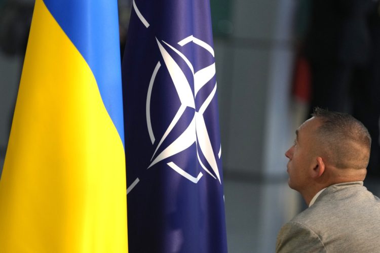Člen protokolu vztyčuje vlajky NATO a Ukrajiny pred mediálnou konferenciou ukrajinského prezidenta Volodymyra Zelenského a generálneho tajomníka NATO Jensa Stoltenberga počas stretnutia ministrov obrany NATO v sídle NATO v Bruseli v stredu 11. októbra 2023 &&äFoto: SITA/AP Photo/Virginia Mayo)