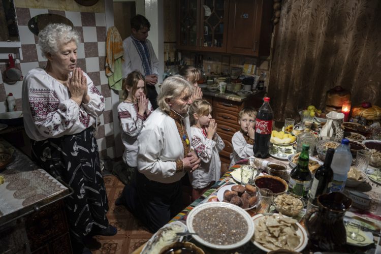 Rodina Zelenčukových sa modlí pred štedrovečernou večerou v ukrajinskej dedine Kryvorivňa v nedeľu 24. decembra 2023 (Foto: SITA/AP Photo/Evgeniy Maloletka)